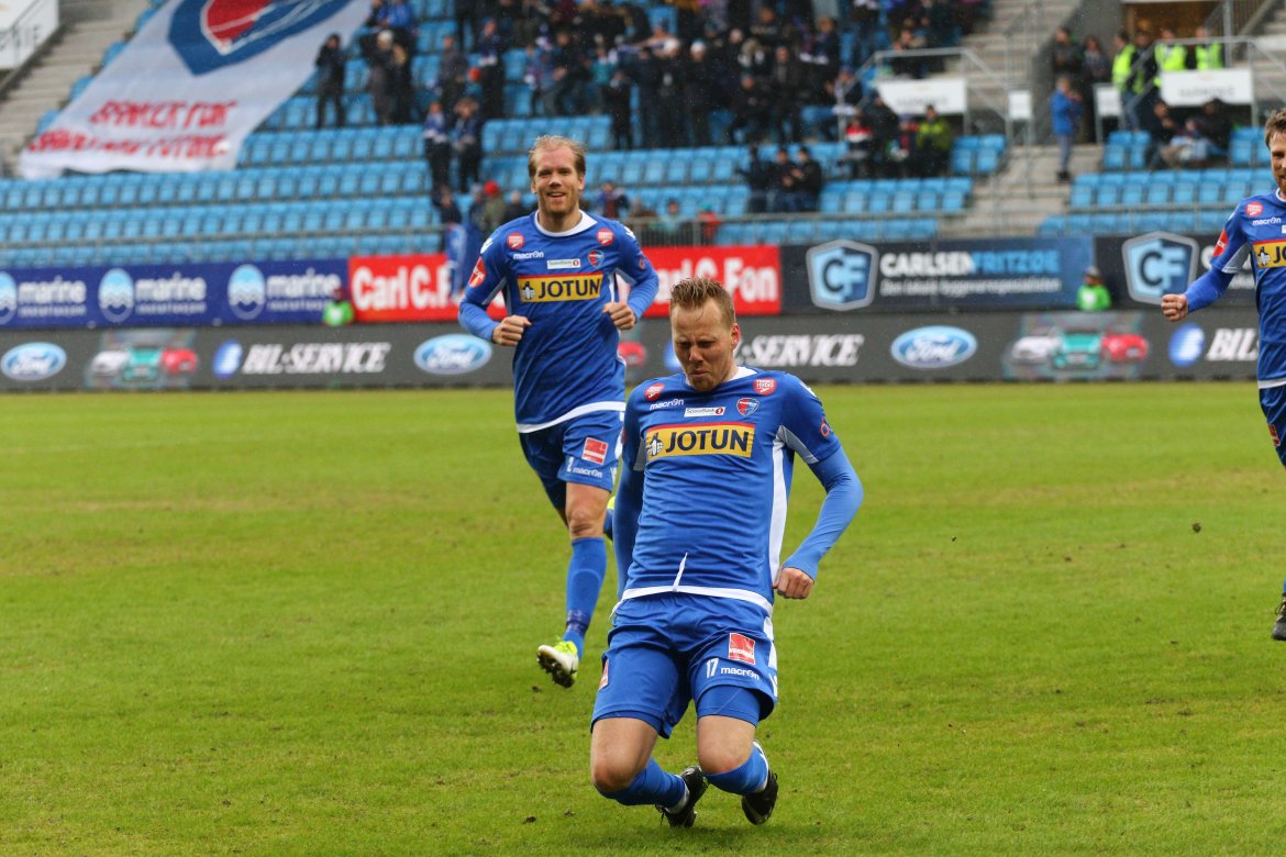 Joackim Olsen Solberg med jublende lagkamerater i bakgrunn. (Foto: Torstein Flåm)